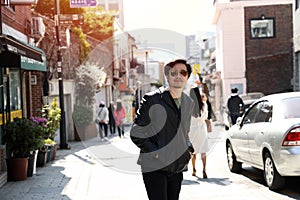 A man wearing sunglasses Black leather jacket Walking on a pedestrian street