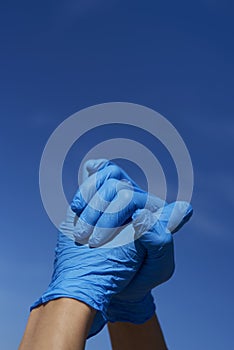 Man wearing surgical gloves clasping his hands