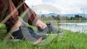 Man wearing trekking shoes and sitting on grass