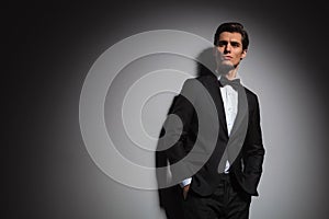 Man wearing tuxedo standing with hands in pockets, looks up