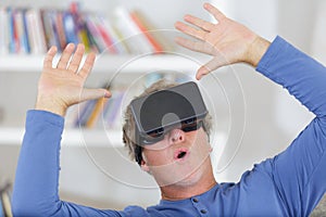 Man wearing virtual reality headset arms raised in air