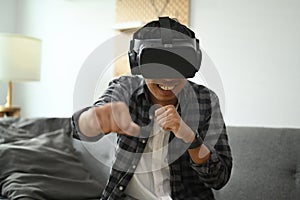 Man wearing virtual reality headset playing simulation boxing game at home.