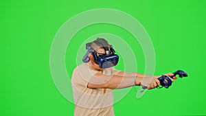 The man wearing VR headset playing in virtual reality game. The man gaming on chroma key green screen background in