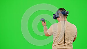 The man wearing VR headset playing in virtual reality game. The man gaming on chroma key green screen background in