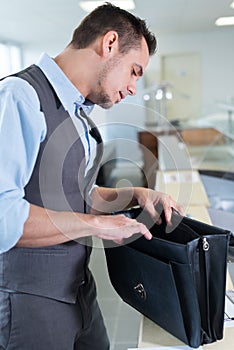 Man wearing waistcoat rifling through satchel