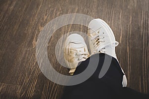 Man wearing white sneakers in black trousers sitting on coffee shop