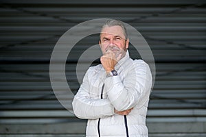 Man wearing a white winter jacket looks thoughtfully into the distance