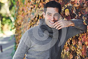 Man wearing winter clothes smiling in autumn leaves background