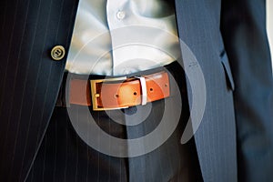 Man wears belt. Young businessman in casual suit with accessories. Fashion and clothing concept. Groom getting ready in