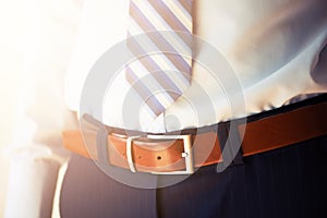 Man wears belt. Young businessman in casual suit with accessories. Fashion and clothing concept. Groom getting ready in