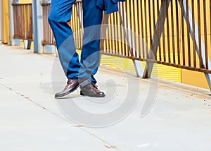 Man wears blue trousers with brown shoes