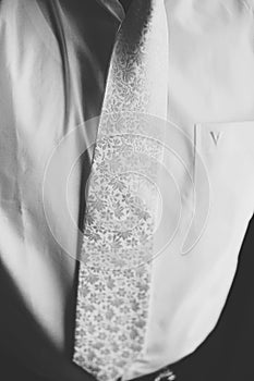 Man wears a white tie with a silver fowers over a white shirt photo