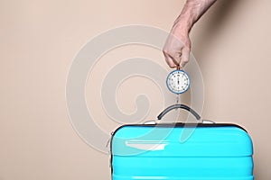 Man weighing stylish suitcase against color background