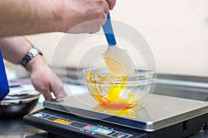 Man weighs caramel in a glass bowl