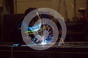 Man welding creating sparks, wearing safety equipment
