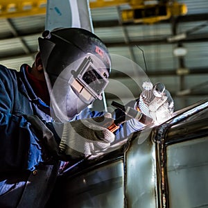 Man welding with reflection of sparks on visor