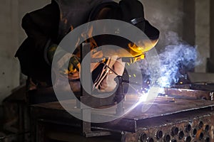 Man welds metal. Worker welding steel in industry with safety mask safety gloves and safety equipment. Metal industry welding