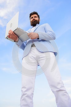 Man well groomed bearded hipster holds laptop blue sky background. Guy formal suit modern technology manager