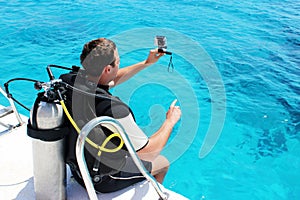 A man in a wet suit, with an aqualung, mask and a balloon. A diver with diving camera in diving gear is preparing to dive