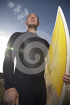 Man In Wetsuit Carrying Surfboard On Beach