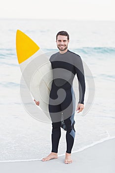 Man in wetsuit with a surfboard on a sunny day