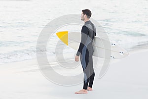 Man in wetsuit with a surfboard on a sunny day