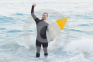 Man in wetsuit with a surfboard on a sunny day