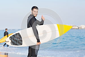 Man in wetsuit with a surfboard on a sunny day