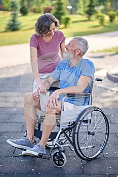 A man in a wheel chair and his wife on a walk in the park