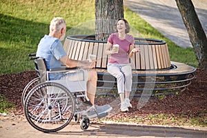 A man in a wheel chair and a woman havinng coffee in the park