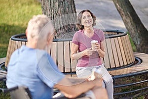 A man in a wheel chair and a woman havinng coffee in the park