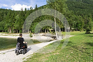 Man in wheelchair in autumnal park near the lake