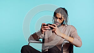 Man in wheelchair feeling sad after losing videogame, playing on mobile phone