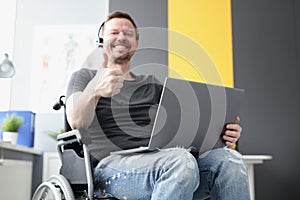 Man in wheelchair with headphones showing thumb up