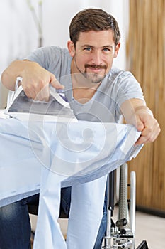 man in wheelchair ironing shirt