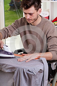 Man on wheelchair ironing shirt