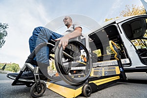 A man in a wheelchair on a lift of a vehicle for people with disabilities