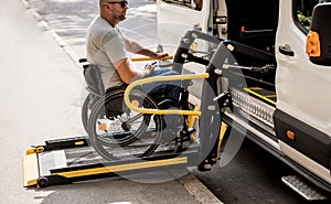 A man in a wheelchair on a lift of a vehicle for people with disabilities