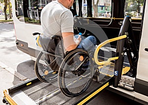 A man in a wheelchair on a lift of a vehicle for people with disabilities