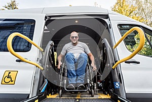 A man in a wheelchair on a lift of a vehicle for people with disabilities