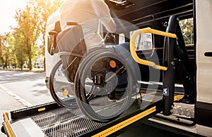 A man in a wheelchair on a lift of a vehicle for people with disabilities