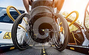 A man in a wheelchair on a lift of a vehicle for people with disabilities