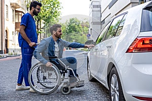 Man in a wheelchair opening a car door