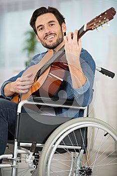 man on wheelchair playing guitar