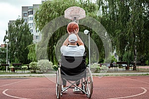 A man in a wheelchair plays basketball on the sports ground. The concept of a disabled person, a fulfilling life, a person with a