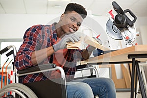 man in wheelchair rubbing down wood with sandpaper