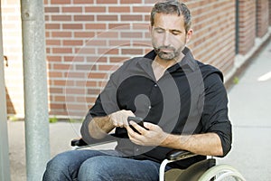 Man in wheelchair texting on his phone