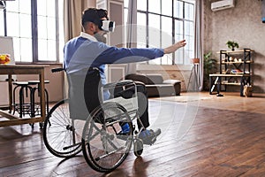 Man in a wheelchair using a VR headset and trying to touch virtual objects