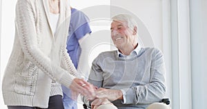 Man, wheelchair and wife or nurse help in clinic for physical therapy, caregiving support or rehabilitation comfort