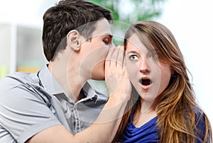 Man whispering in the ear of his surprised wife